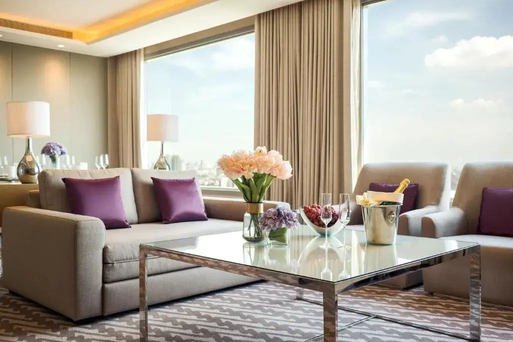 Couchtisch mit Blumenstrauß und Sektkühler im hellen Wohnbereich mit Stadtblick.