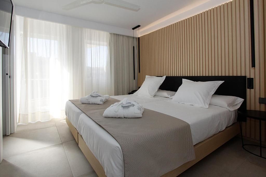 Helles Hotelzimmer mit Doppelbett, hölzerner Wandverkleidung und hellem Fliesenboden.