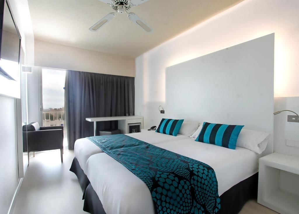 Hotelzimmer mit Doppelbett, türkisfarbener Bettwäsche und Zugang zum Balkon.