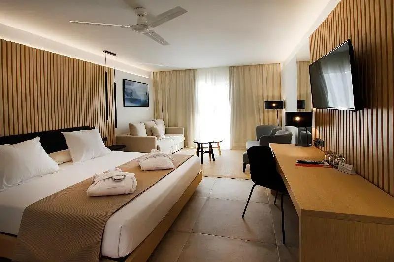 Geräumiges Hotelzimmer mit Doppelbett, Sitzecke und einem Holzschreibtisch.