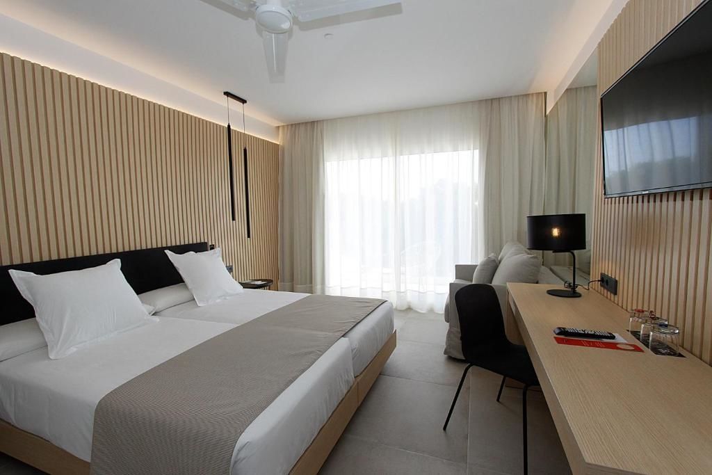Modernes Hotelzimmer mit Doppelbett, Sitzgelegenheit, Schreibtisch und großem Fenster.