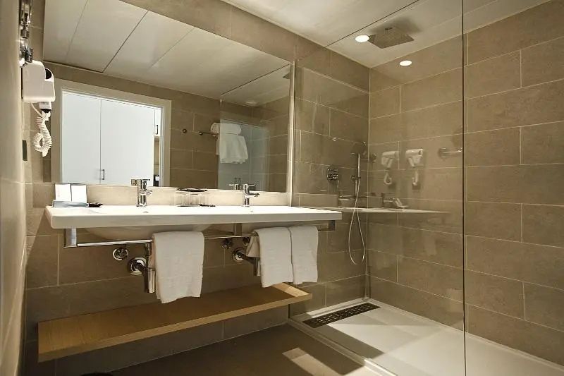 Modernes Badezimmer mit Doppelwaschbecken, großem Spiegel und bodengleicher Glasdusche