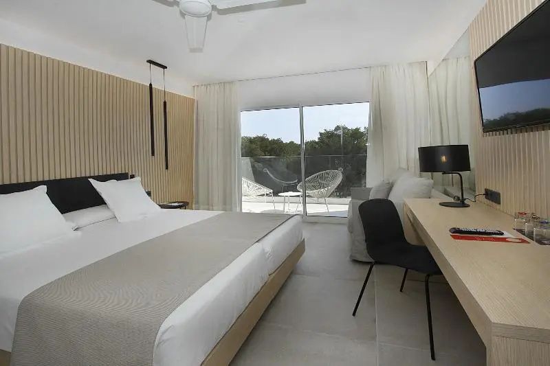 Hotelzimmer mit Doppelbett, Schreibtisch und großer Glasfront zur Terrasse.