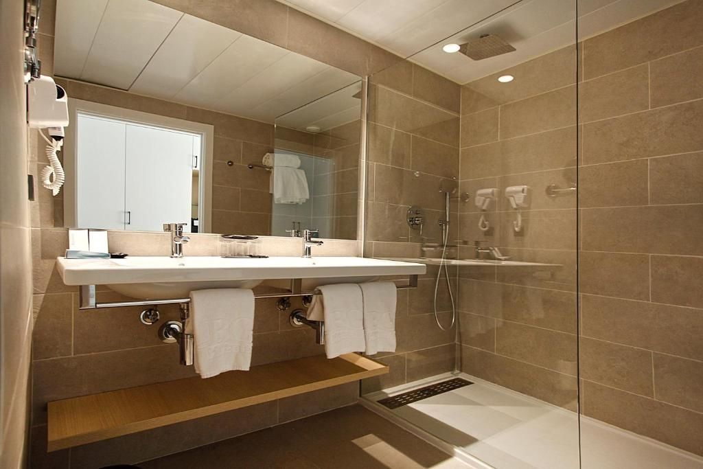 Badezimmer mit Doppelwaschtisch, großem Spiegel und einer bodengleichen Dusche.