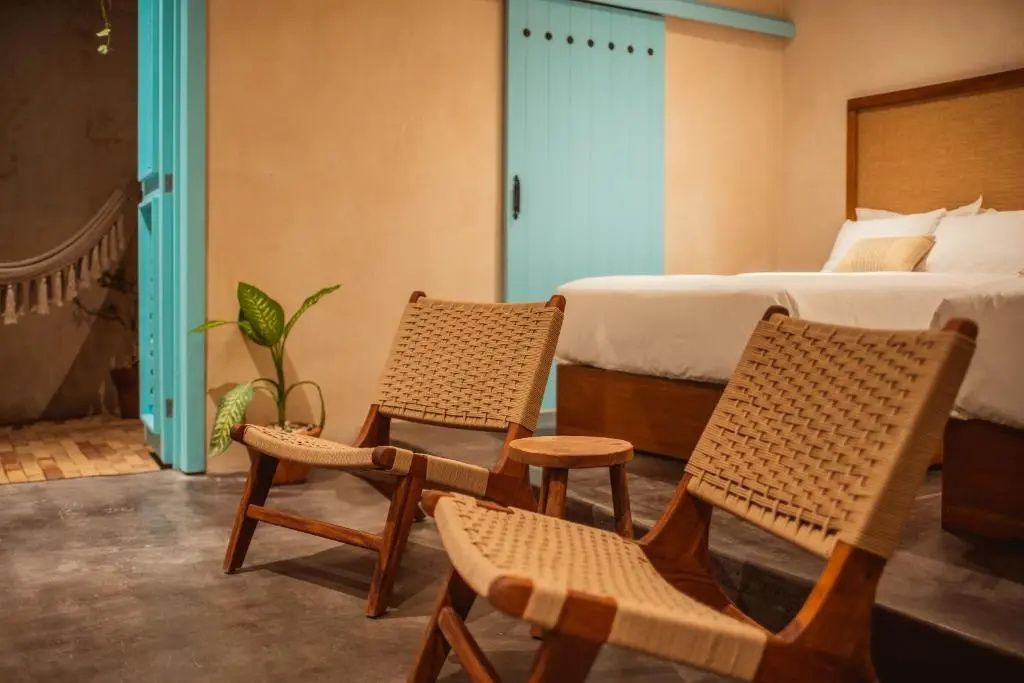 Sitzbereich im Hotelzimmer mit zwei Holzstühlen, einem Beistelltisch und einer hellblauen Schiebetür.