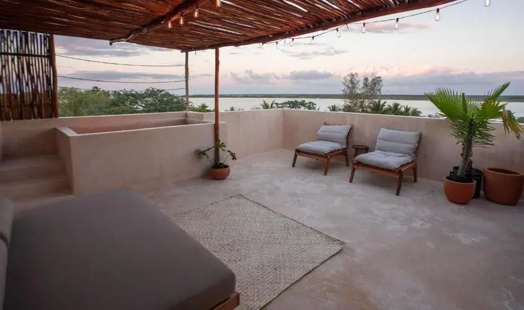 Dachterrasse mit Holzüberdachung, Liegestühlen und Blick auf die umliegende Lagune.