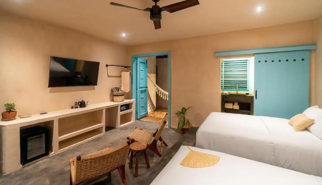 Geräumiges Hotelzimmer mit Betten, Fernseher, Sitzmöbeln und Blick zur Terrasse.