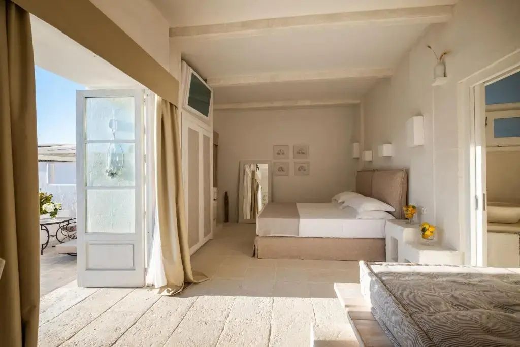 Helles Hotelzimmer mit Doppelbett, beigefarbenen Vorhängen und einer Terrassentür