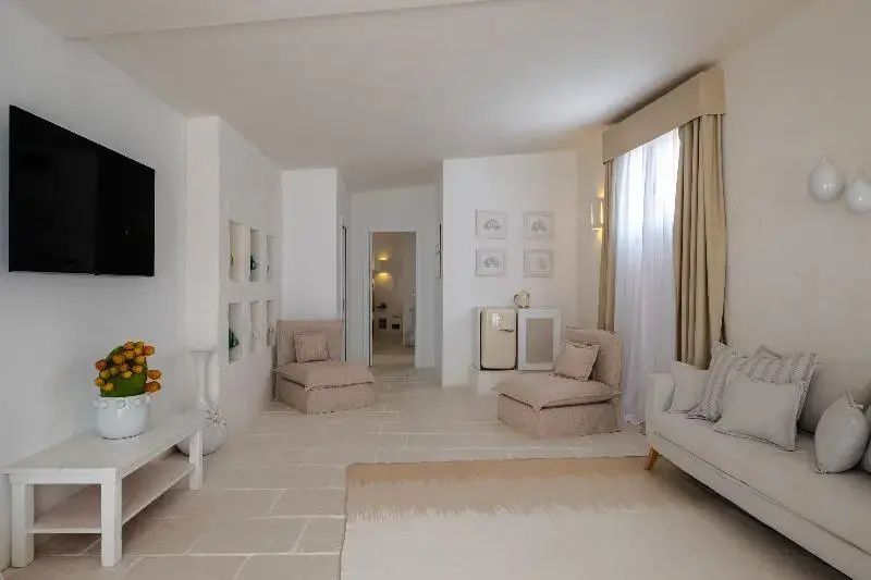 Heller Wohnbereich mit beigen Sesseln und Steinboden in einer Suite.