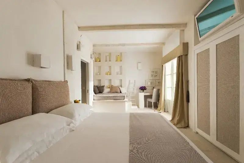 Helles Hotelzimmer mit Doppelbett im Vordergrund und Sitzecke im Hintergrund.