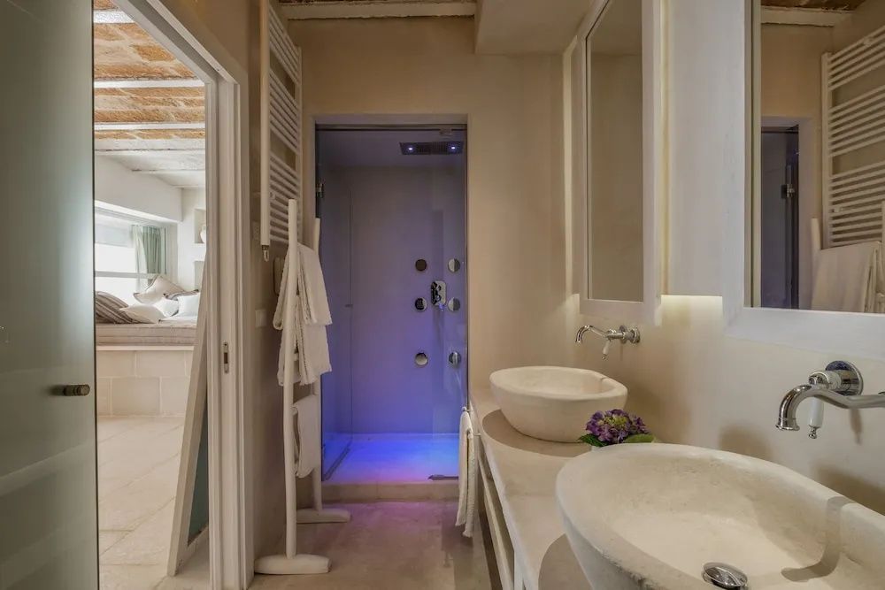Badezimmer mit zwei Aufsatzwaschbecken und einer modern beleuchteten Dusche.