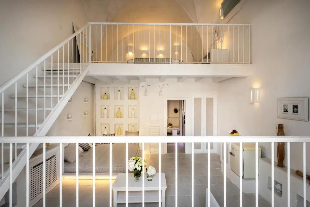 Maisonette Zimmer mit weißem Gewölbe, Empore mit Geländer und Sitzbereich unten.