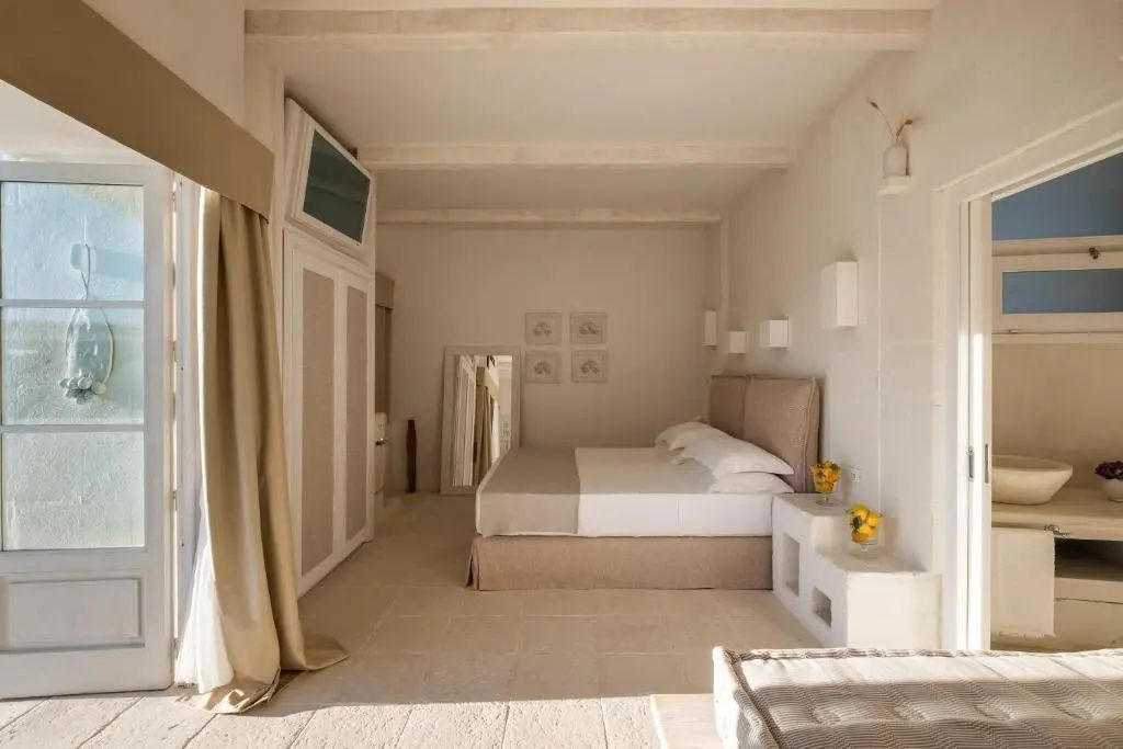 Schlafbereich mit großem Doppelbett, Einbauschrank und Wandspiegel in hellen Tönen