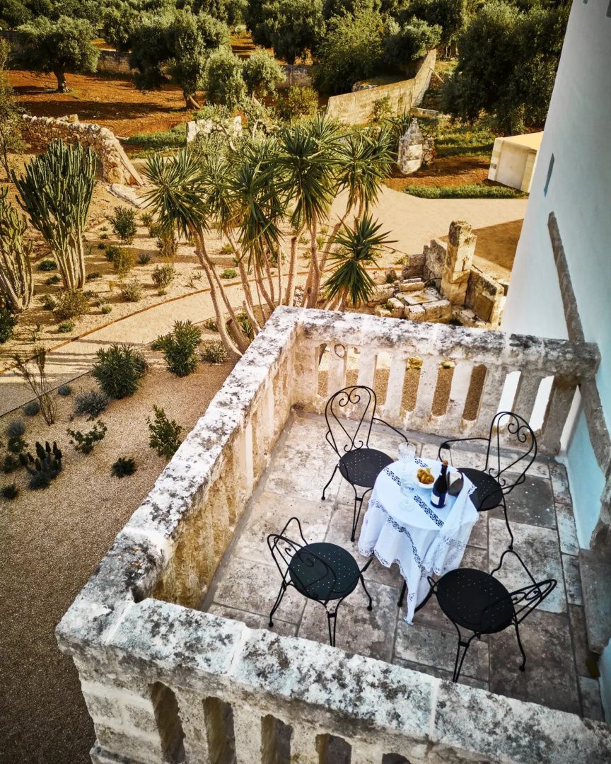 Blick von einem Steinbalkon mit Tisch und Stühlen auf den Gartenbereich.