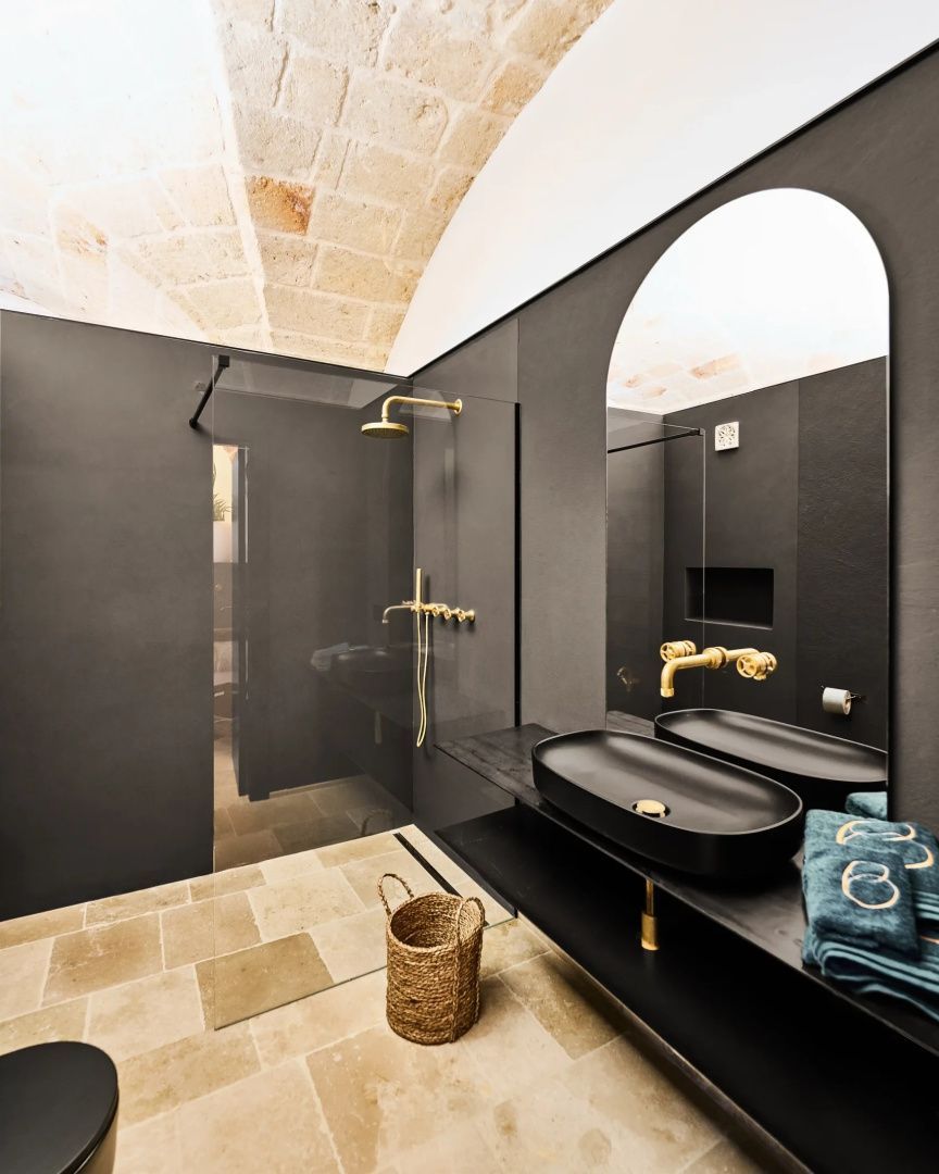 Badezimmer mit schwarzem Waschtisch, goldenen Armaturen und Dusche.