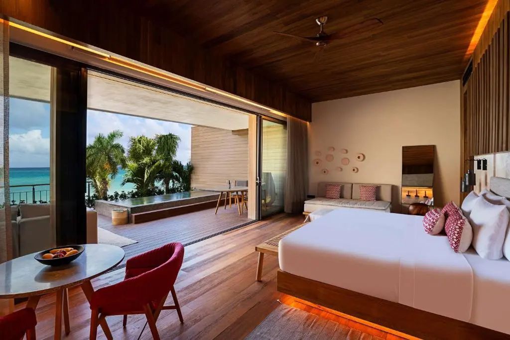 Blick aus dem Schlafzimmer auf eine Terrasse mit privatem Pool und Palme.