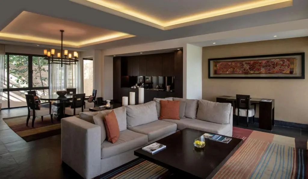 Geräumiger Wohnbereich mit grauem Ecksofa, dunklem Couchtisch und Bar im Hintergrund.