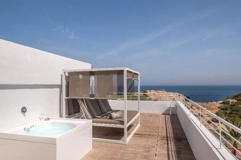 Terrasse mit überdachtem Daybed, Whirlpool und freiem Blick auf das blaue Meer.