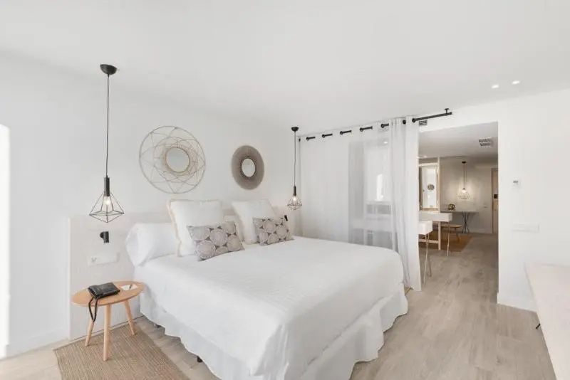 Helles Hotelzimmer mit weißem Doppelbett, runden Wanddekorationen und einem Vorhang.