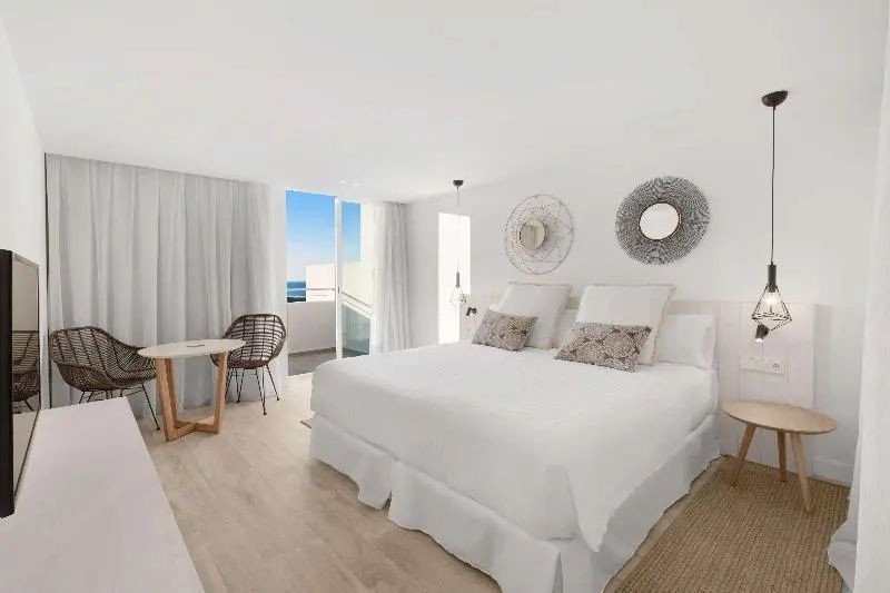 Helles Schlafzimmer mit großem Doppelbett, Tisch und Blick durch die Balkontür
