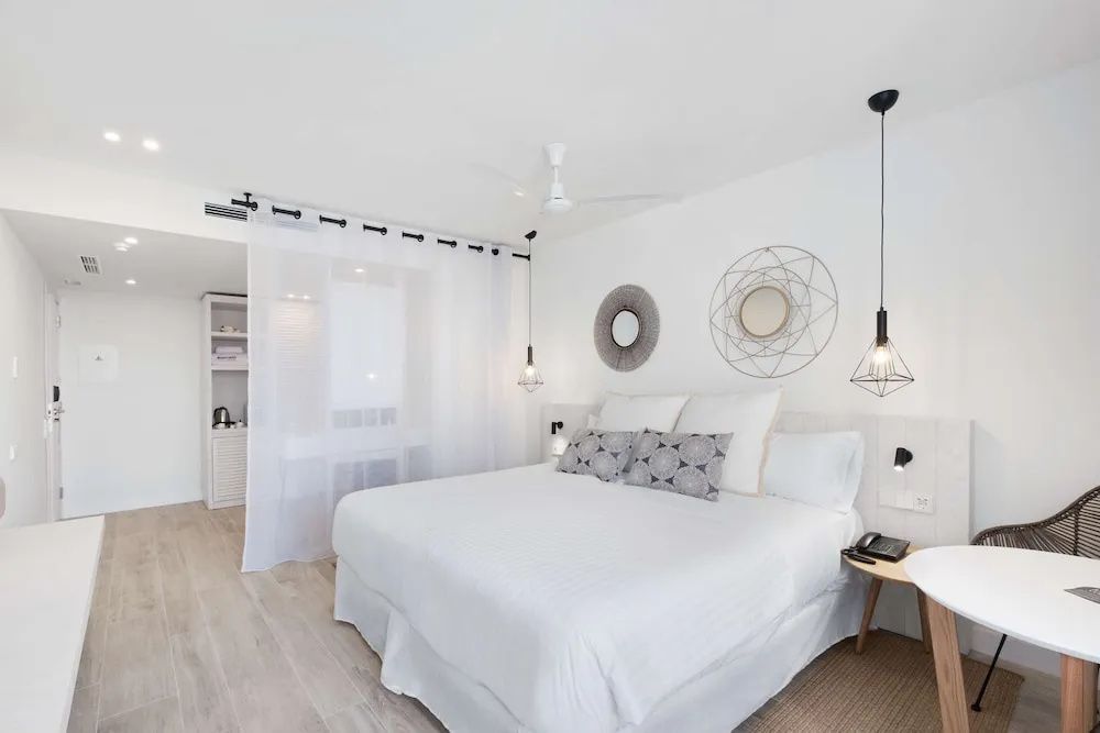Helles Hotelzimmer mit weißem Doppelbett, Nachttisch und Wanddekoration