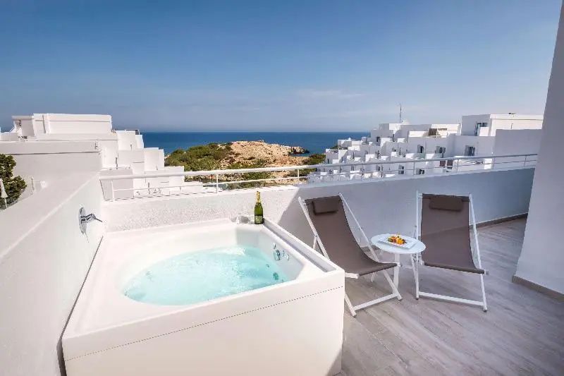 Terrasse mit privatem Whirlpool, zwei Liegestühlen und freiem Blick auf das Meer.