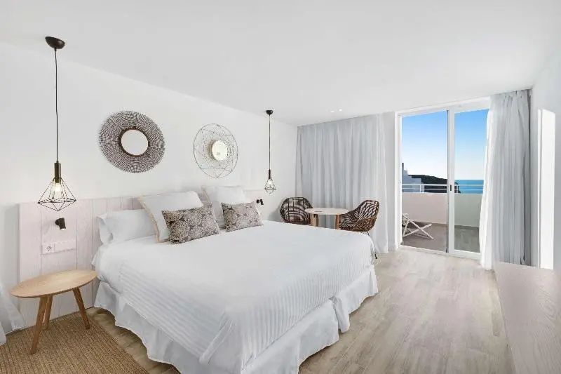 Hell eingerichtetes Schlafzimmer mit Doppelbett, Wanddekoration und Balkonzugang.