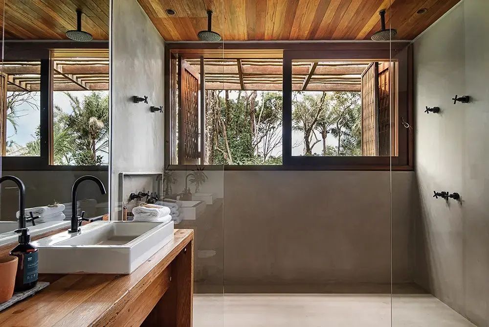 Badezimmer mit Regendusche, Waschtisch aus Holz und Fenster mit Blick ins Grüne.