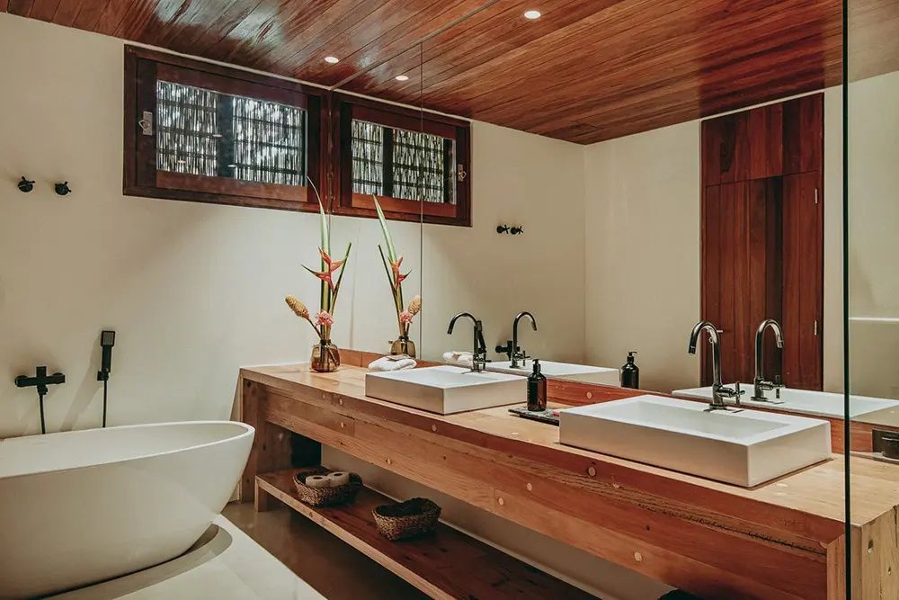 Badezimmer mit einem Holzwaschtisch, zwei Waschbecken und einer freistehenden Wanne.