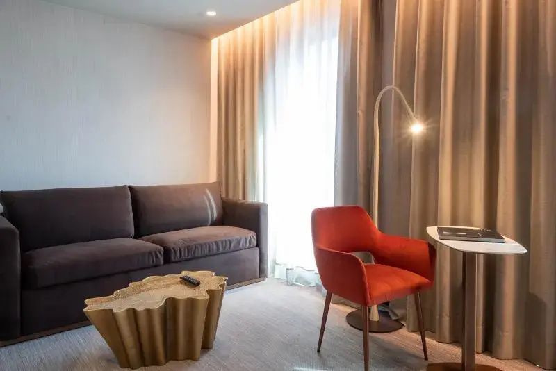 Sitzbereich im Hotelzimmer mit braunem Sofa, rotem Sessel und Couchtisch.