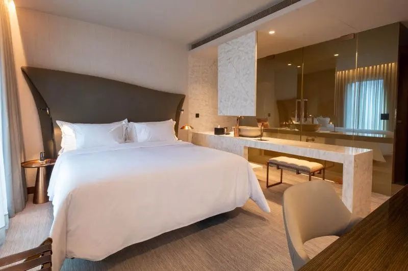 Modernes Hotelzimmer mit Doppelbett und integriertem Waschtisch aus Marmor.