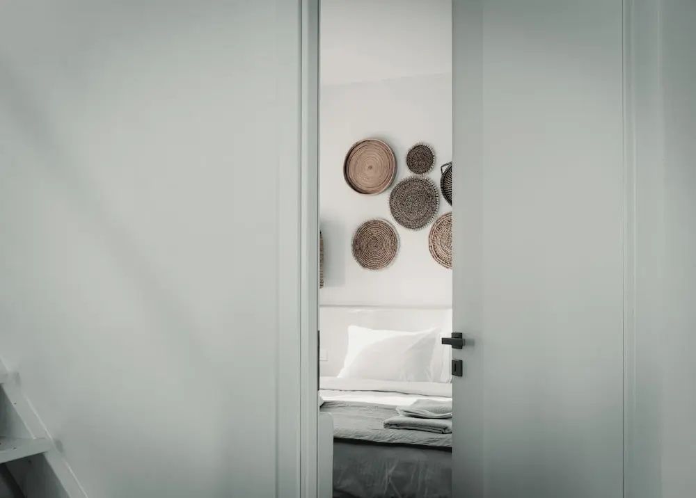Blick durch den Türrahmen auf ein Kissen und geflochtene Wandteller im Zimmer.