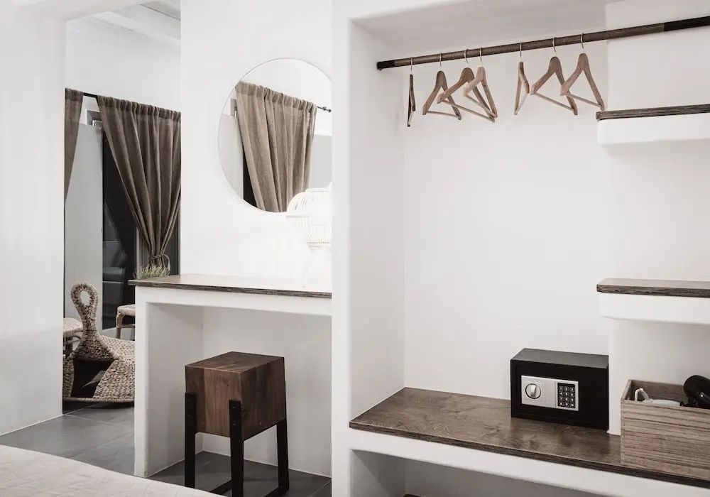 Weißer Einbauschrank mit Kleiderbügeln, Minisafe, Schminktisch und rundem Spiegel.