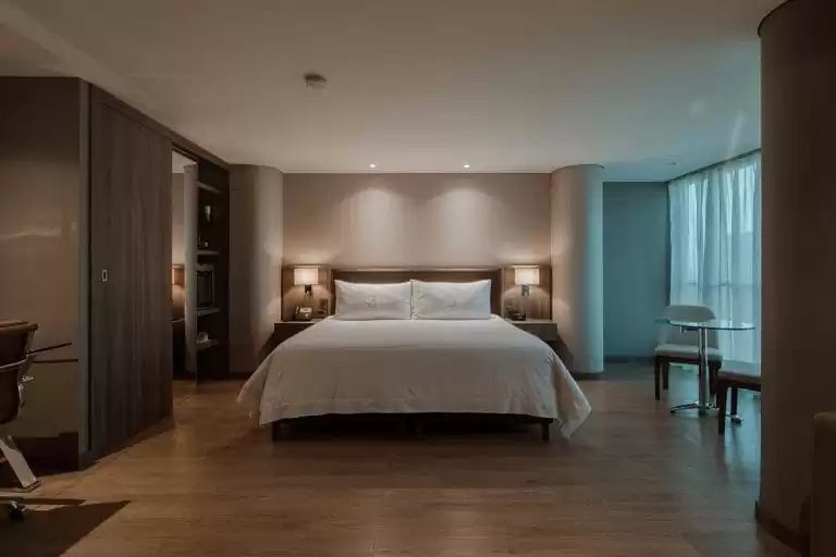 Modernes Hotelzimmer mit großem Doppelbett und dezenter Wandbeleuchtung.