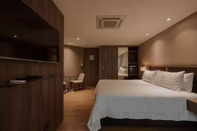 Hotelzimmer mit großem Bett, Flachbild-TV an der Holzwand und Sitzgelegenheit.