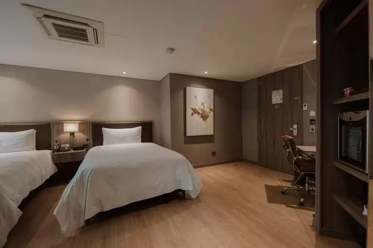 Zimmer mit Einzelbett, Parkettboden, Schreibtisch und Wandbild.