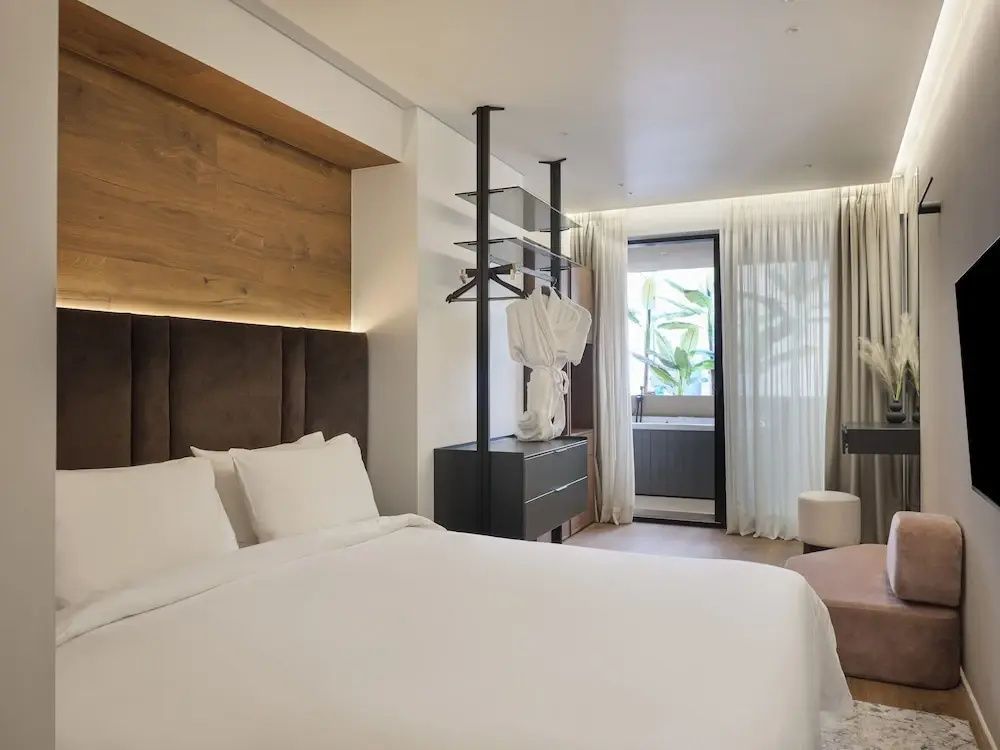 Hotelzimmer mit Doppelbett, offenem Kleiderständer und Blick auf den Balkon