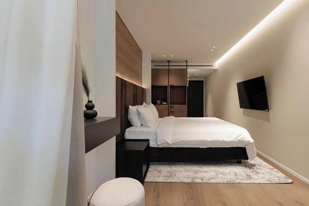 Schlafzimmer mit großem Doppelbett, Parkettboden und Flachbildfernseher.