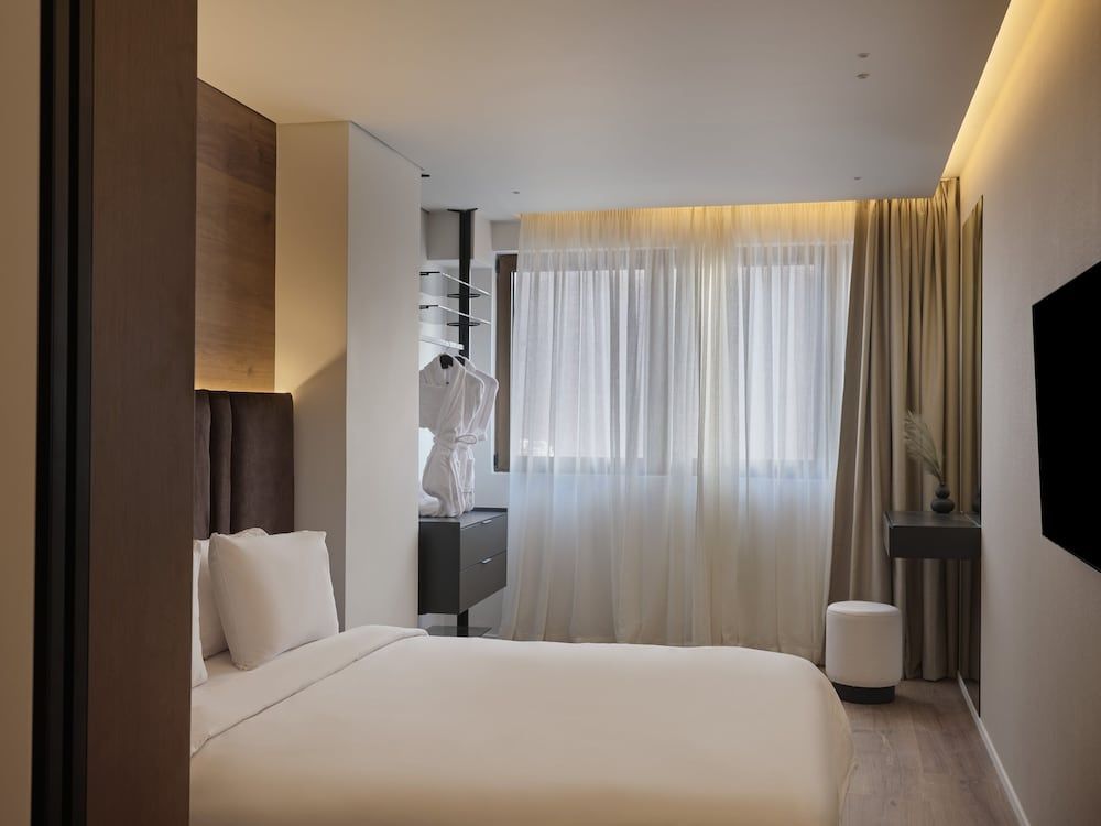 Schlafzimmer mit weiß eingedecktem Bett und bodentiefen Vorhängen