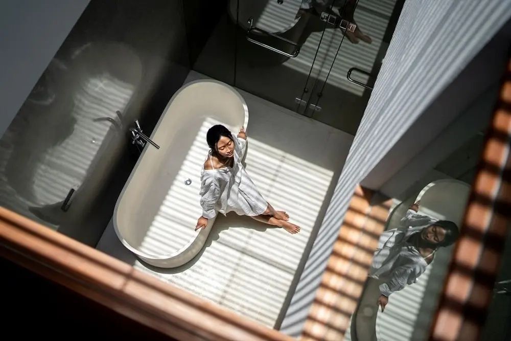 Blick von oben auf eine freistehende weiße Badewanne in einem lichtdurchfluteten Badezimmer.