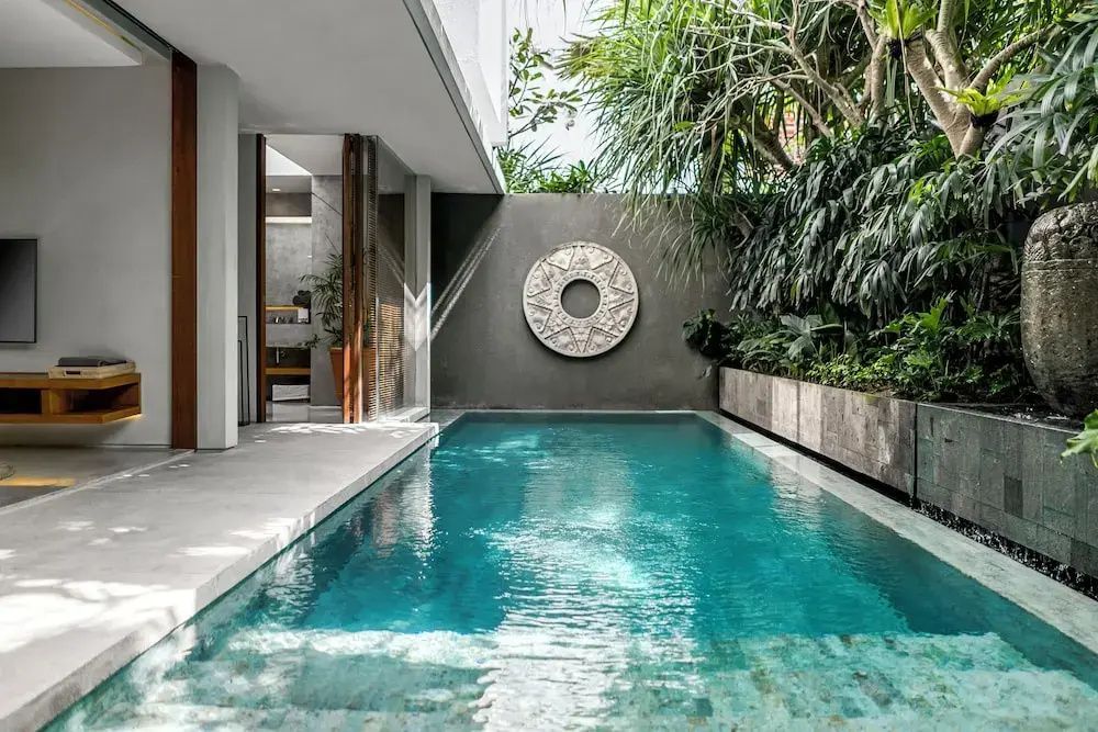 Private Poolanlage einer Villa mit runder Wanddekoration und tropischen Pflanzen.