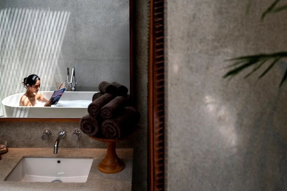 Waschbecken im Badezimmer mit gerollten braunen Handtüchern auf einem Holzständer