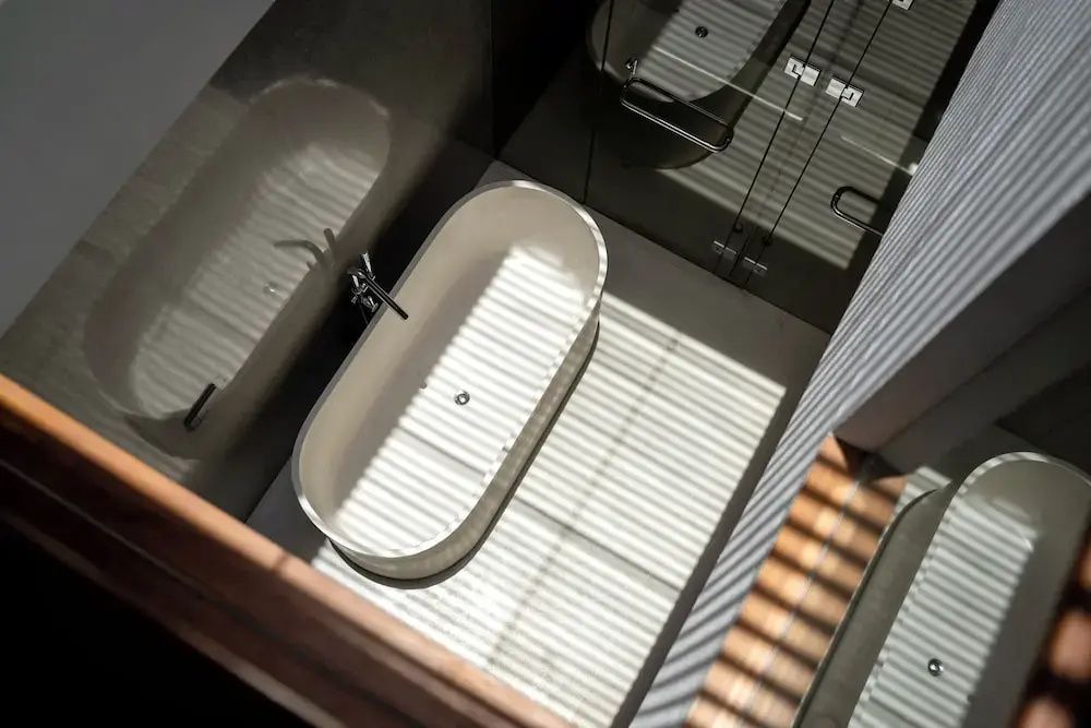 Freistehende Badewanne von oben gesehen bei Sonneneinstrahlung durch Holzlamellen