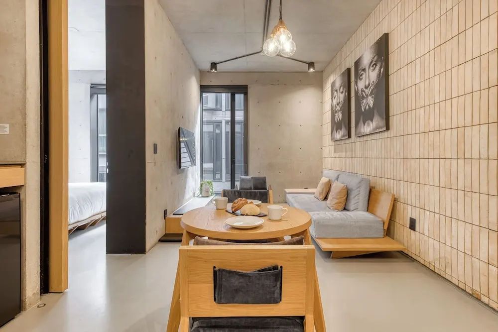 Wohnbereich eines Appartements mit rundem Esstisch, Sofa und Wänden aus Beton.