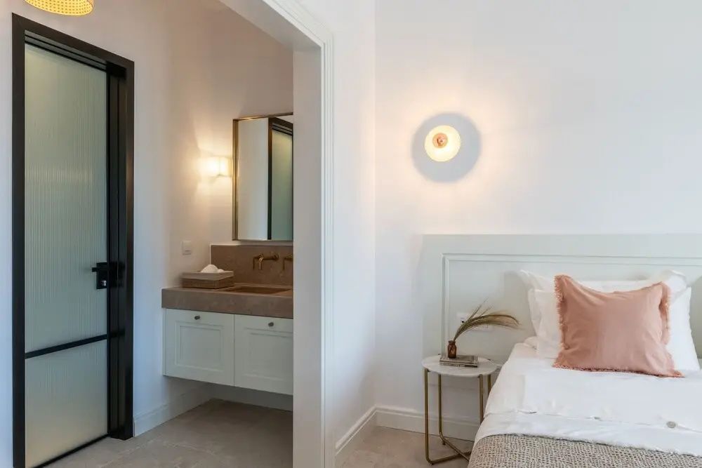 Schlafbereich mit Blick durch einen Durchgang auf den Waschbereich im Badezimmer.