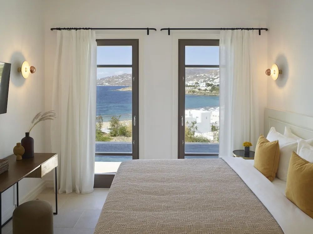 Blick durch zwei bodentiefe Fenster im Schlafzimmer auf das Meer und die Küste.