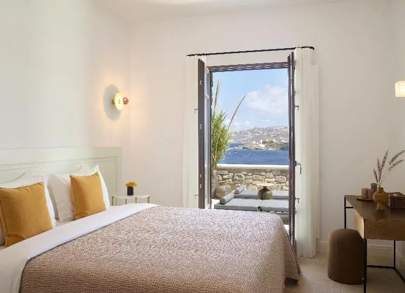 Schlafzimmer mit geöffneter Terrassentür und Blick auf den Außenbereich sowie das Meer.