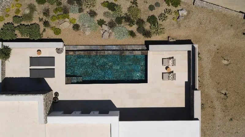 Draufsicht auf einen rechteckigen Swimmingpool und eine Terrasse mit Sonnenliegen.