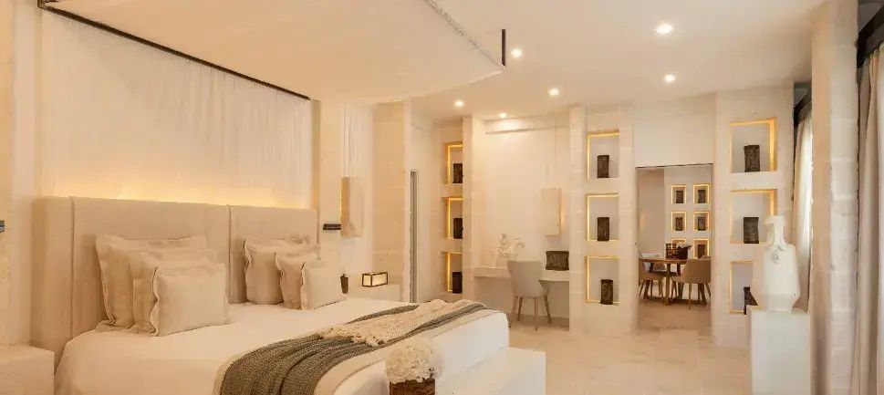 Hell gestaltetes Hotelzimmer mit großem Doppelbett und einem Arbeitsbereich an der Wand.
