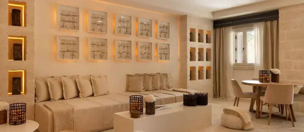 Wohnbereich im Zimmer mit beigem Sofa, Bilderserie an der Wand und kleinen Wandnischen.